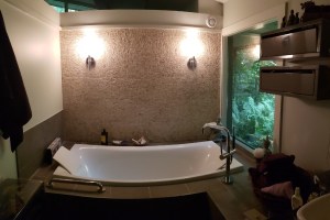 Elegant bathroom with modern soaking tub, textured tile accent wall, and dual wall sconces