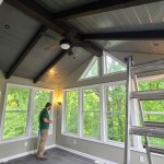 Contractor installing interior finishes in a bright sunroom with slate tile