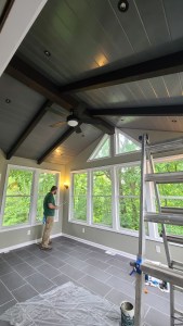 Contractor installing interior finishes in a bright sunroom with slate tile