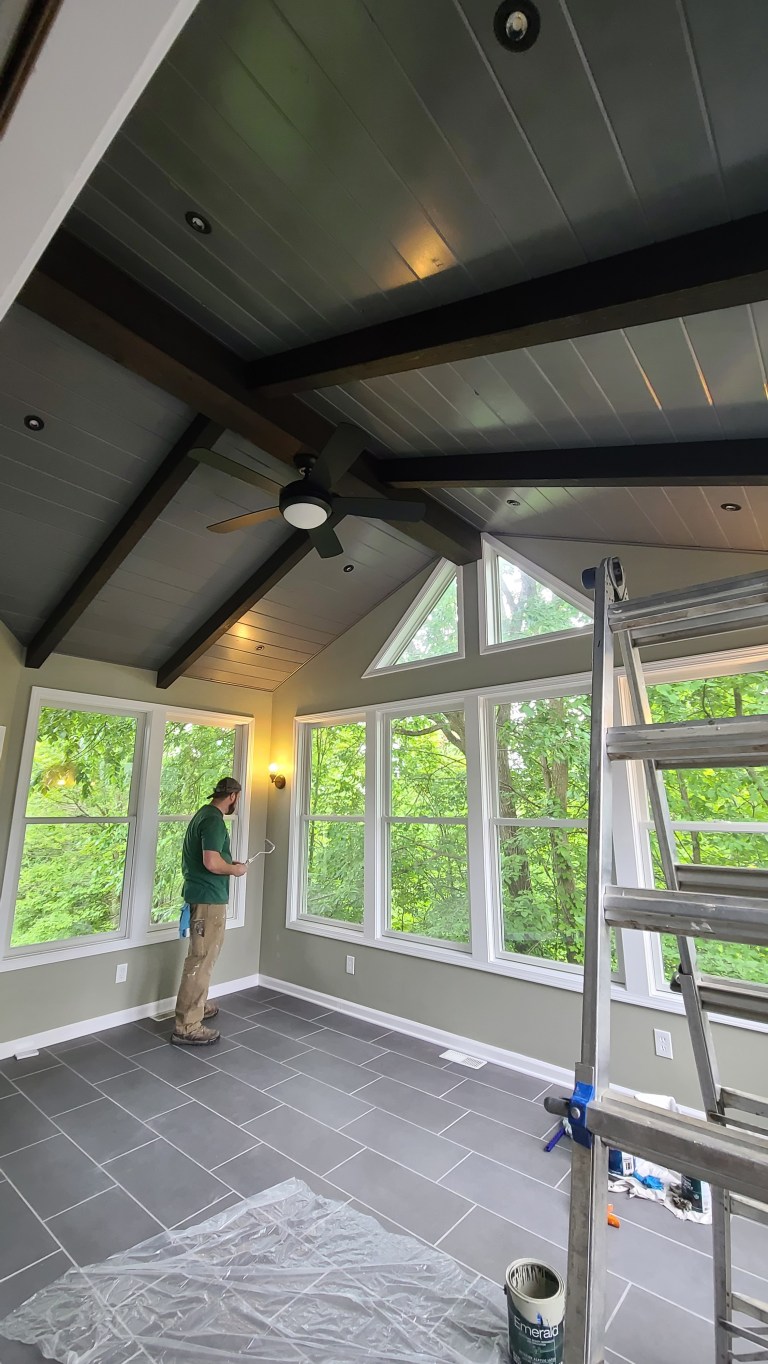 Contractor installing interior finishes in a bright sunroom with slate tile