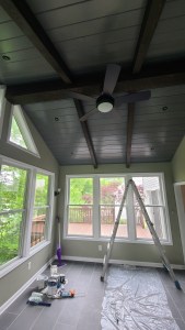 Bright four-season room with wood beam ceiling and scenic views