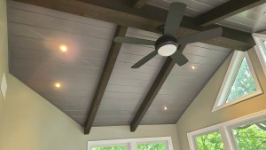 Close-up of vaulted sunroom ceiling with exposed beams, recessed lights, and ceiling fan