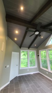 Ceiling fan installation in sunroom with recessed lighting and beam design