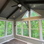 Four-season sunroom with vaulted ceiling, fan, and large windows overlooking trees