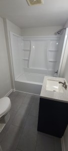 Acrylic tub and white sink with brushed nickel fixtures in a remodeled bathroom