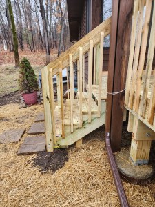 Newly rebuilt exterior deck stairs with fresh wood railing and step supports
