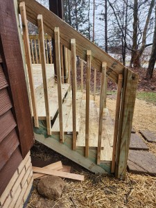 Side view of new wooden deck stairs and handrail leading to backyard