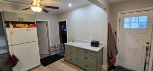 Bright remodeled kitchen with sage green lower cabinets, white walls, and modern wood flooring