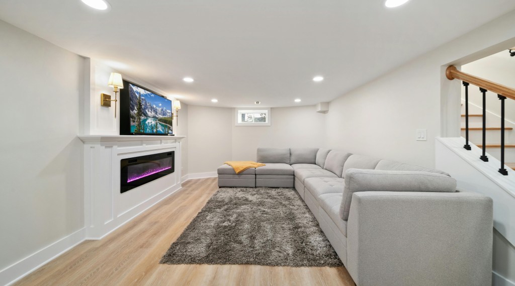 Modern basement with light wood flooring, entertainment setup, and pool table in Akron home remodel.