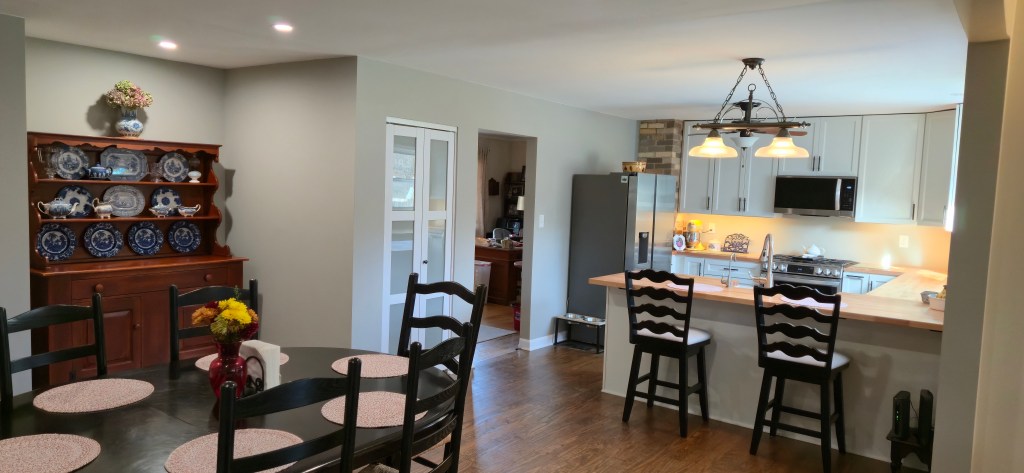 Dining room remodel with updated flooring, recessed lighting, neutral paint, and an antique hutch completed by a local remodeling contractor.
