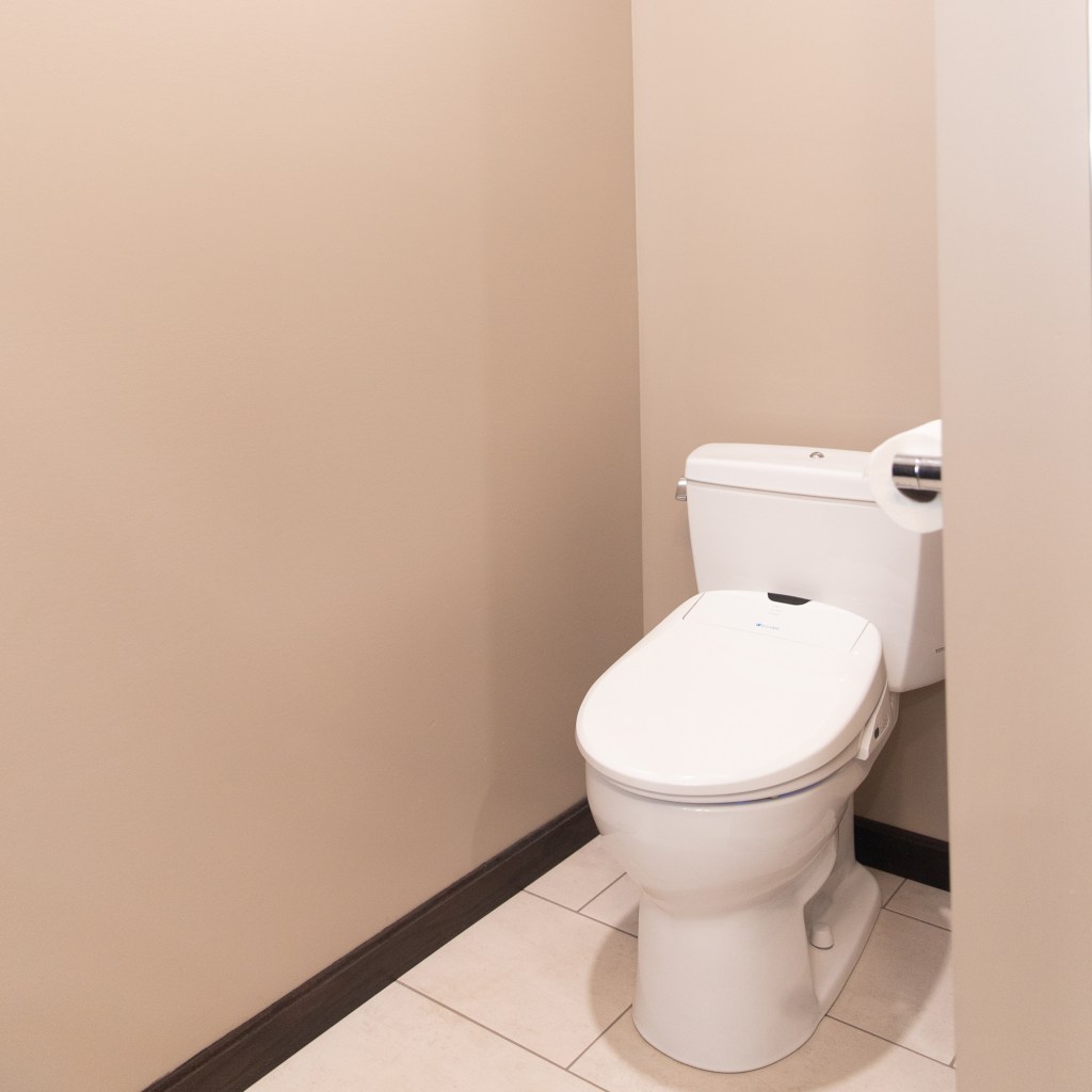 Remodeled bathroom toilet area with modern toilet, neutral wall color, and tiled flooring completed by a local general contractor.