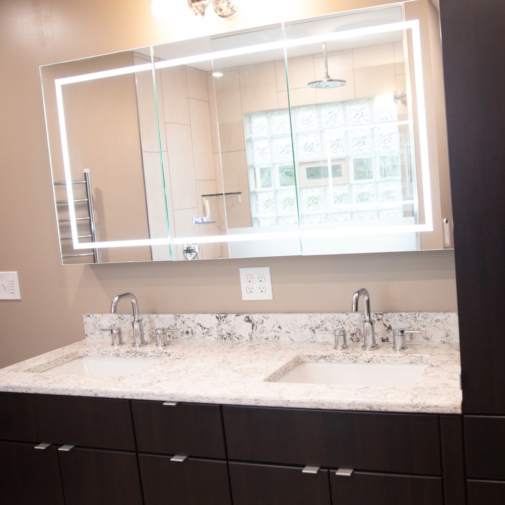 Double bathroom vanity with quartz countertop, undermount sinks, chrome fixtures, and modern cabinetry installed by local remodeling contractors.