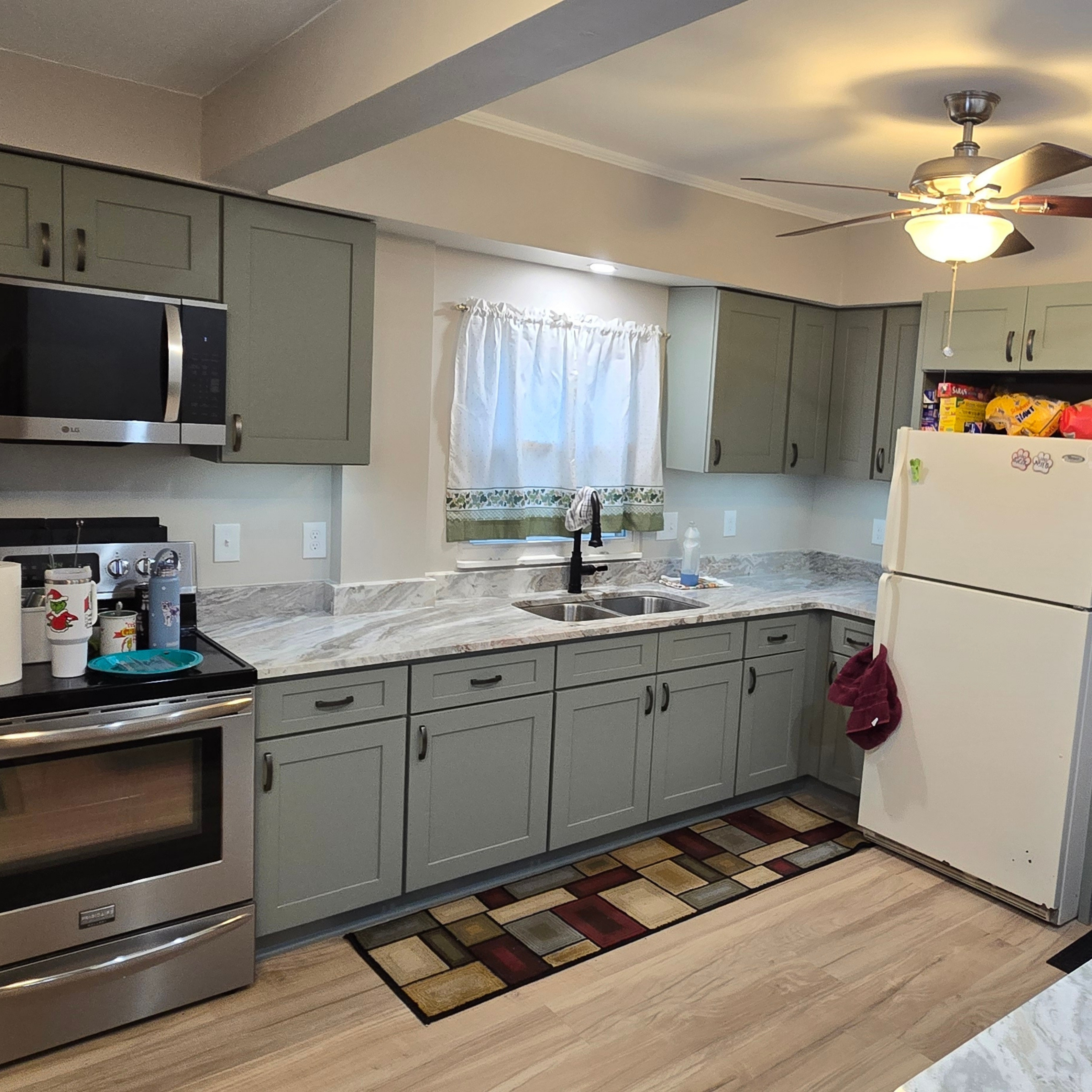 Updated kitchen with sage green Shaker cabinets, marble-look countertops, stainless appliances, under-cabinet lighting, and a double-bowl sink.