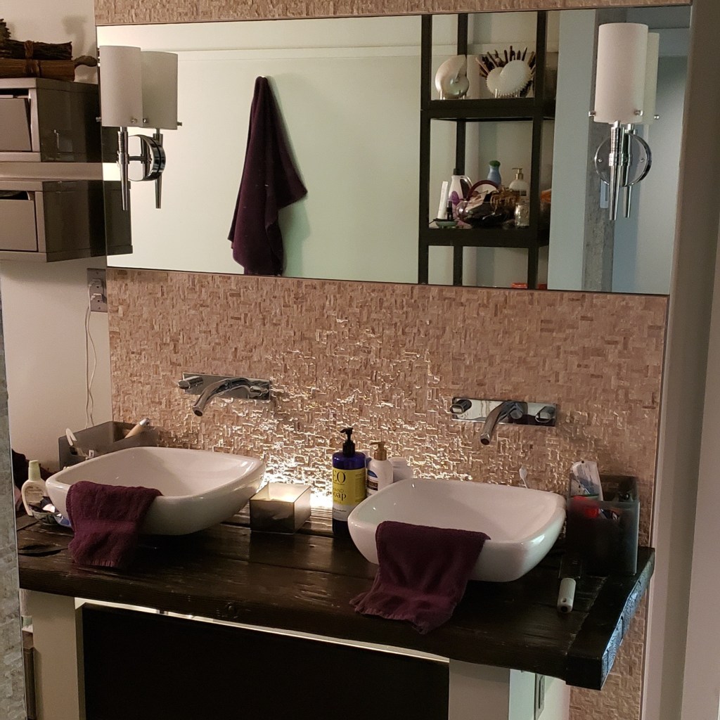 Floating double vanity with vessel sinks, wall-mounted faucets, and backlit mirror