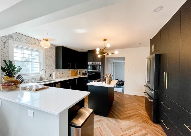 Spacious kitchen remodel with island, modern lighting, black cabinets, and wood flooring