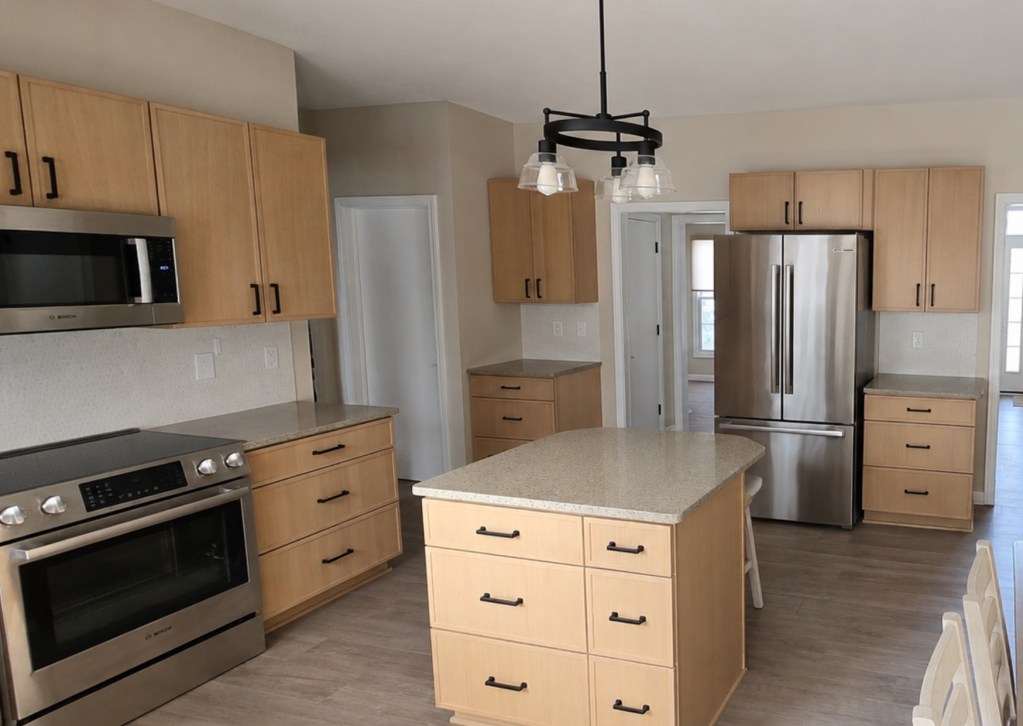 Modern kitchen remodeling in Akron OH featuring custom wood cabinets, oversized island, stainless steel appliances, updated lighting, and open concept layout by Butler Building.