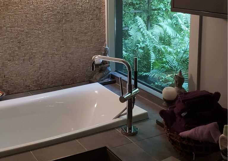 Luxury bathroom remodeling in Akron OH featuring freestanding soaking tub, modern tub filler, textured accent wall, and spa-inspired design.