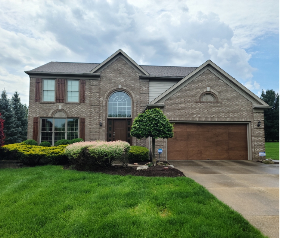 Custom wood-look garage door installation in Akron OH on luxury brick home with modern exterior upgrades and updated curb appeal.