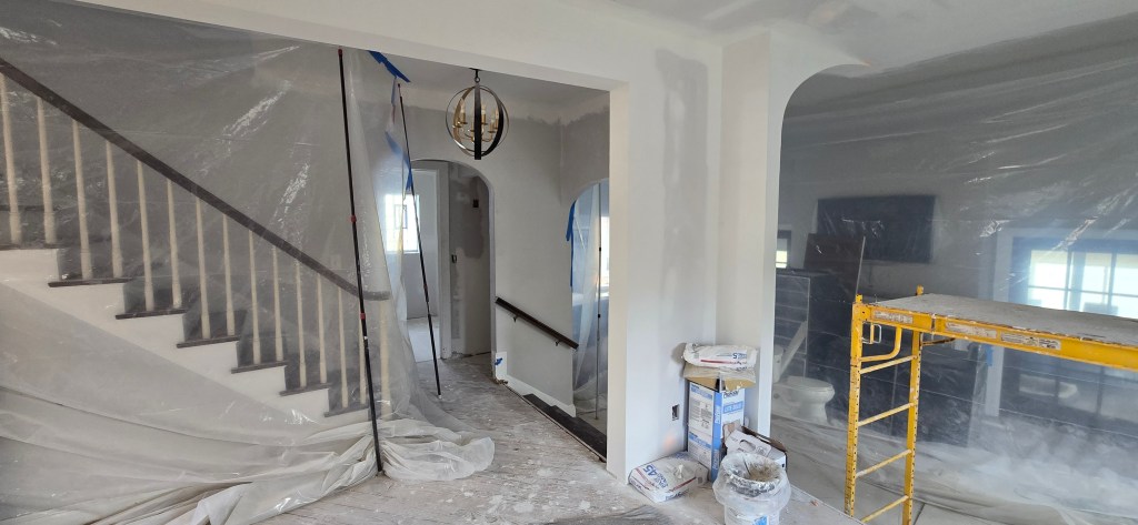 Kitchen remodel under construction featuring exposed brick chimney, vaulted ceiling framing, recessed lighting, drywall finishing, and utility sink in Akron, Ohio.