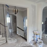 Kitchen remodel under construction featuring exposed brick chimney, vaulted ceiling framing, recessed lighting, drywall finishing, and utility sink in Akron, Ohio.
