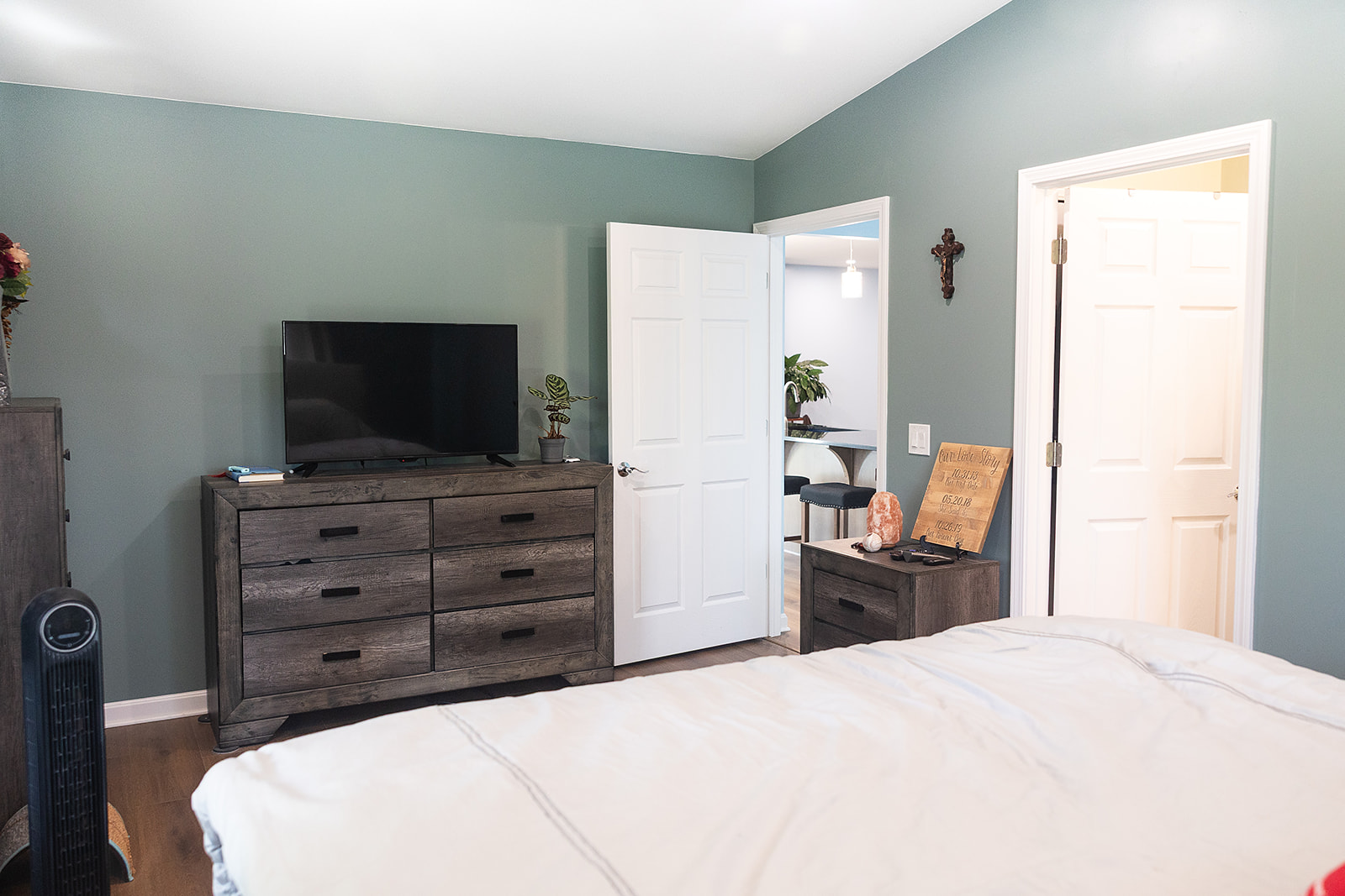 Finished bedroom in North Royalton home addition with green walls, white trim, wood flooring and adjoining remodeled spaces.
