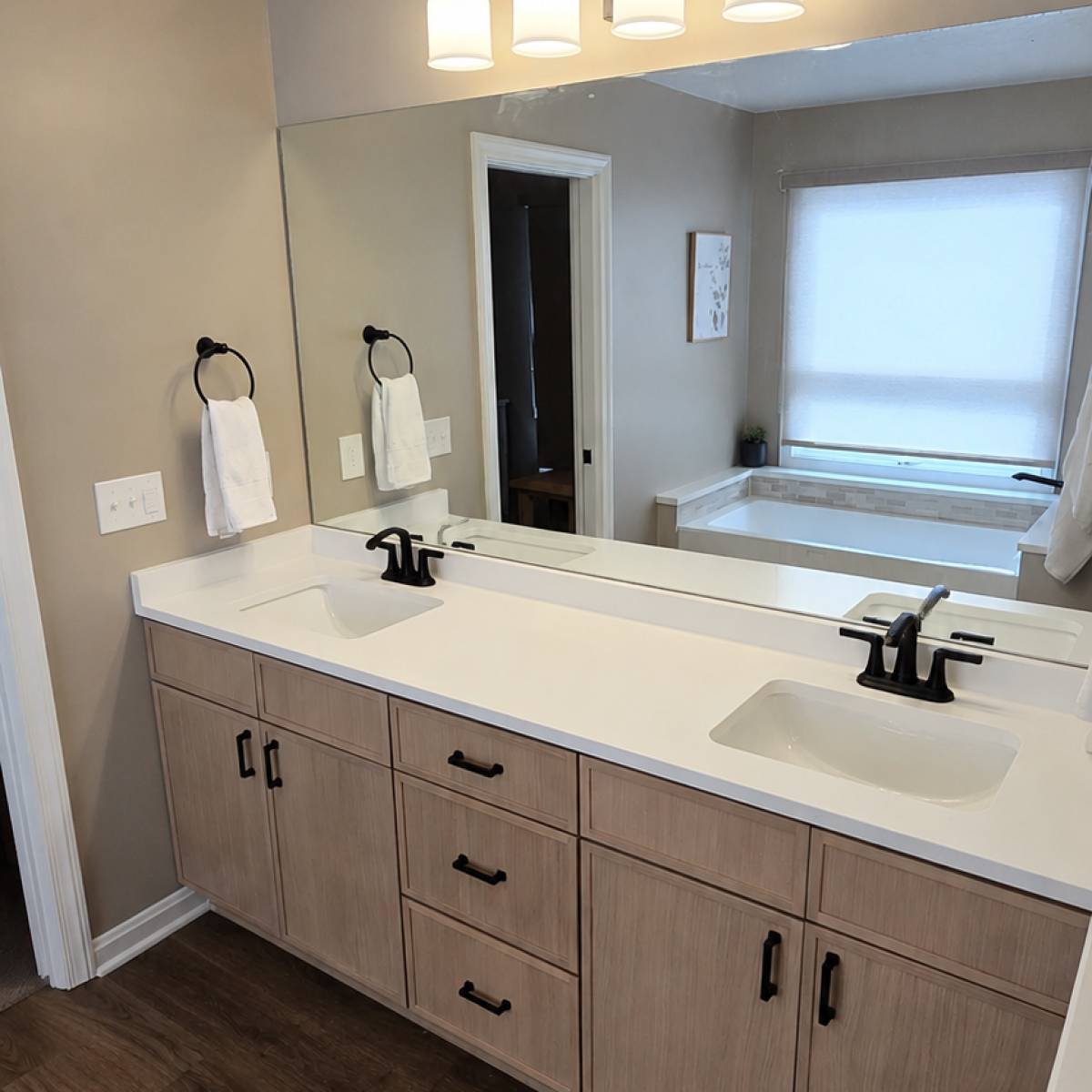 Master bathroom remodeling in Akron OH featuring custom double vanity, quartz countertops, matte black fixtures, oversized mirror, and modern bathroom lighting.