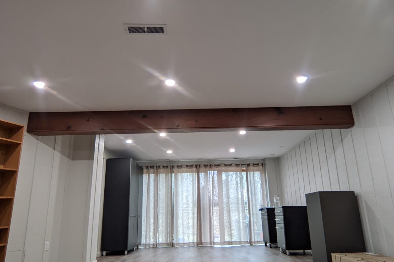 Finished basement remodel in Akron with recessed lighting and wood beam ceiling detail